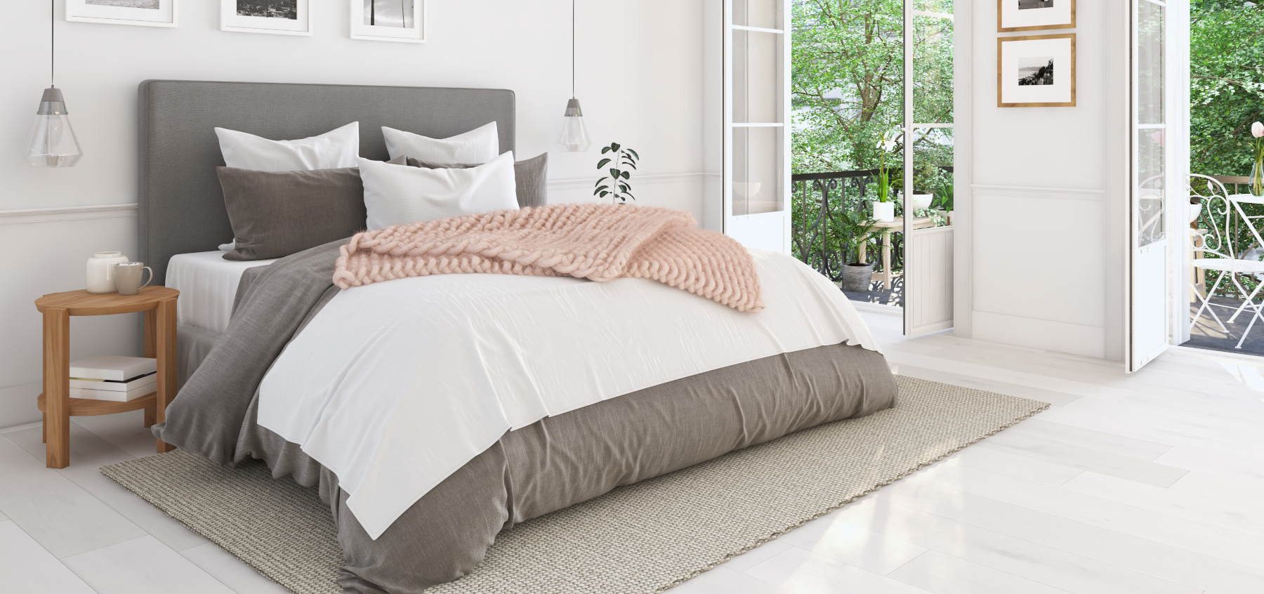Lit double bien dressé avec une couette blanche et une couverture rose pâle sur le dessus, dans une chambre lumineuse et
