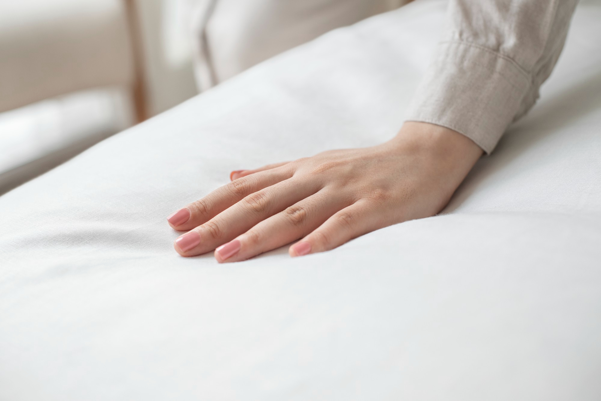 Main: Une main posée sur une couette blanche.